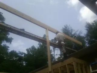 Carpenter setting a ridge beam over a new addition frame — Ice Dam Removal by Roofing Brothers in Peconic