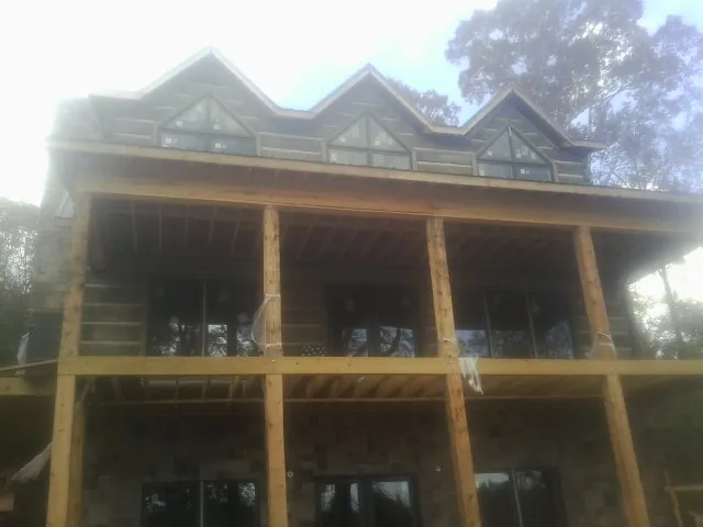 Dormers and porch framing on a large log home under construction — Roof Coating work by our crew in Peconic