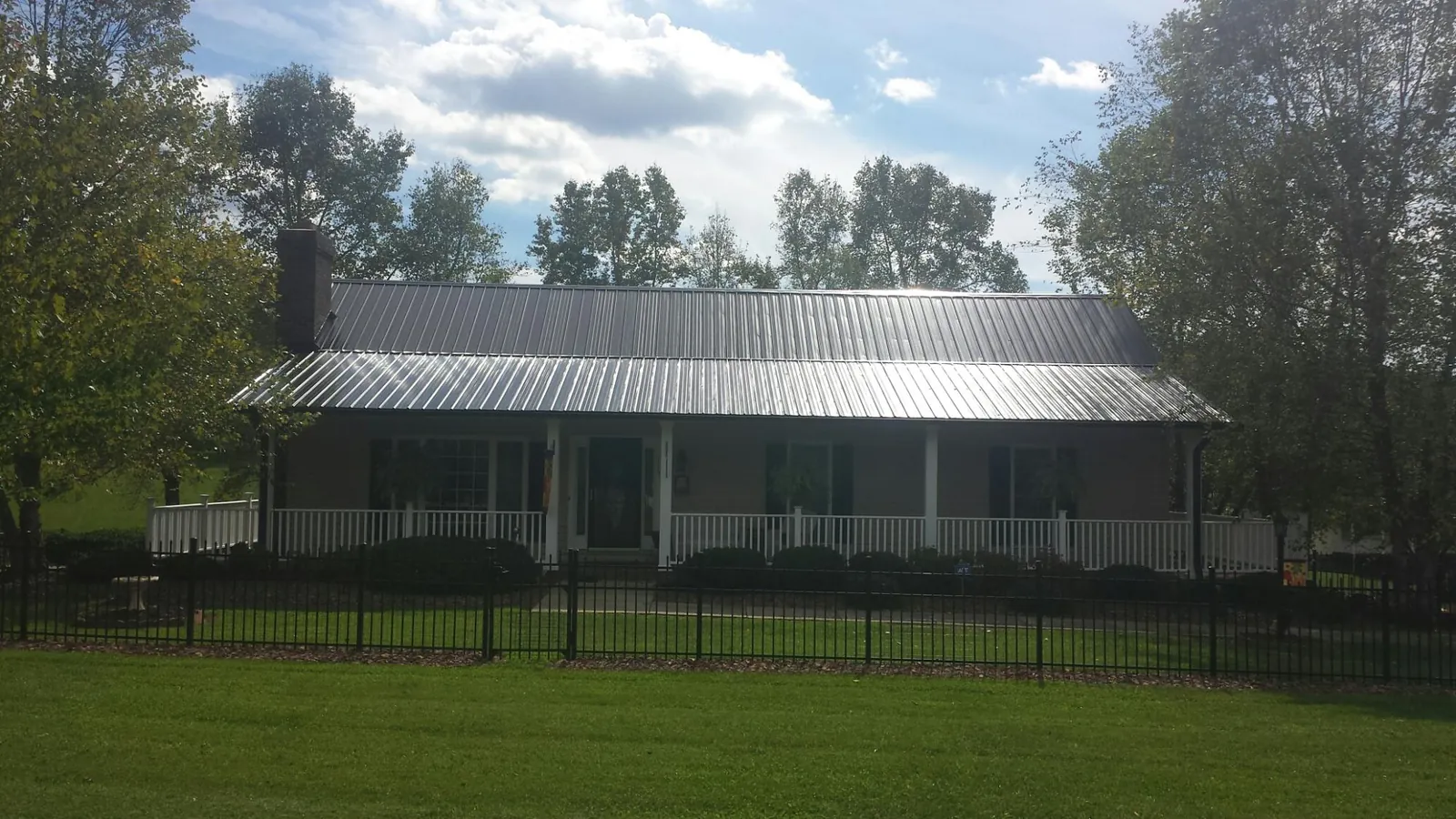 Gray metal roof on a brick ranch with a full width front porch — Gutter Guard Installation work by our crew in Peconic