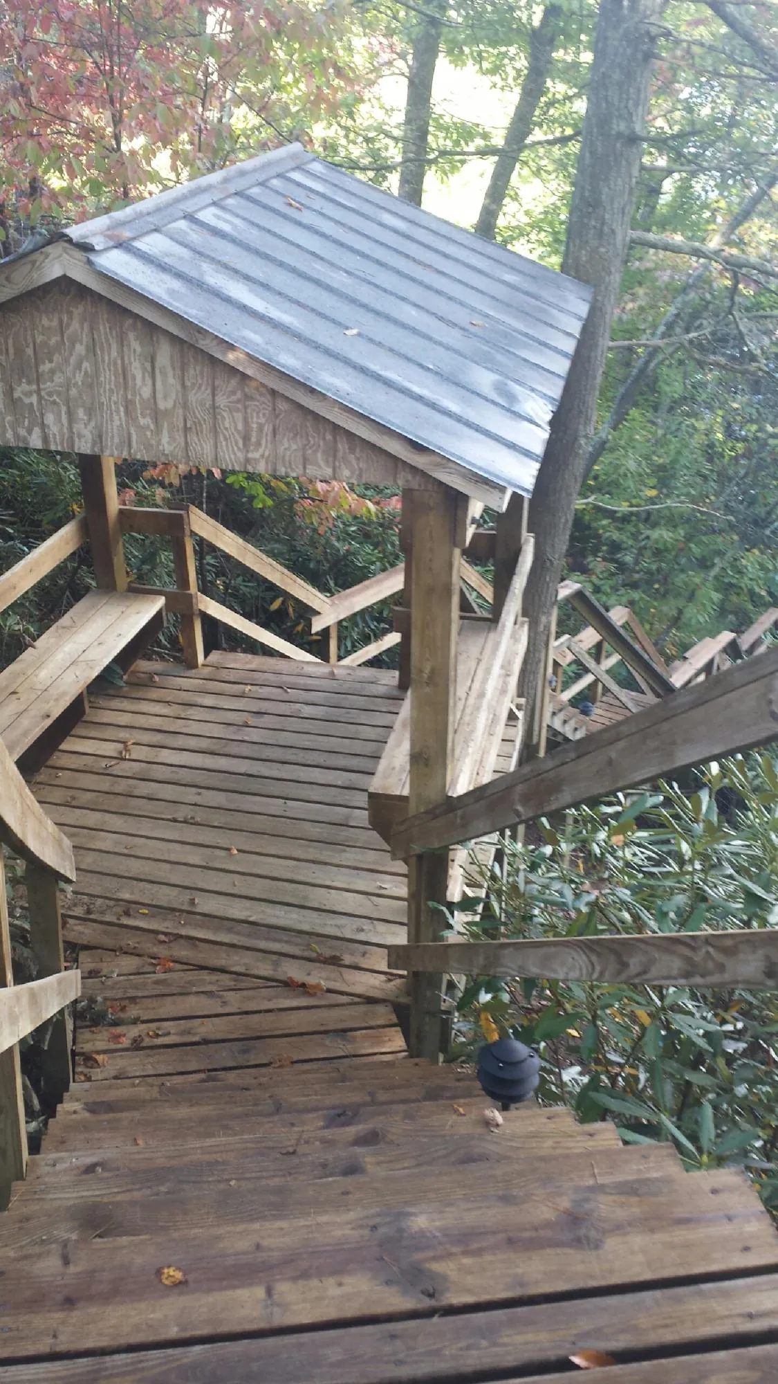 Metal roofed shelter over wooden steps on a wooded walkway — Skylight Repair & Installation work by our crew in Peconic